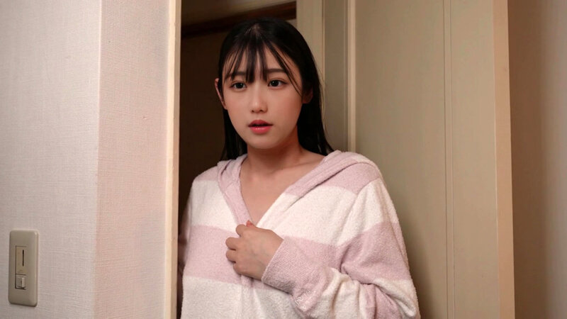 白と淡いピンクのルームウェア姿で室内ドア付近に立つ女性のサンプル画像