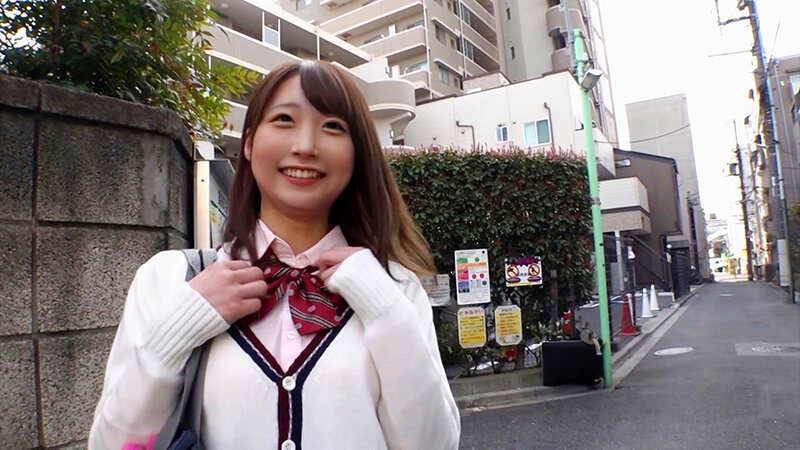 街中で赤いリボンに両手を添え、カメラへ明るく微笑む制服風衣装の女性