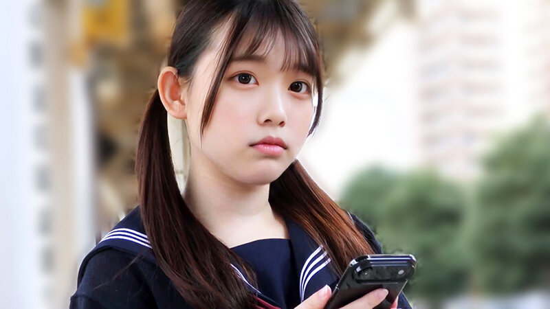 濃紺のセーラー服風衣装を着たツインテール姿で、スマートフォンを持ちまっすぐ見つめる屋外のサンプル画像