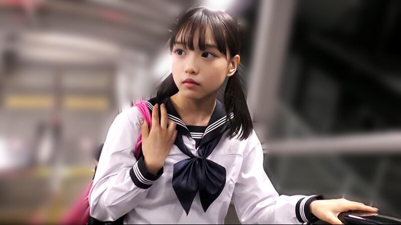 白と黒の制服風衣装にピンクのリュックを合わせた人物が、駅構内らしい背景で振り返る場面
